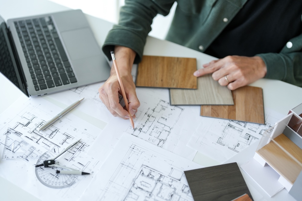 architect working on plans at his desk with a laptop