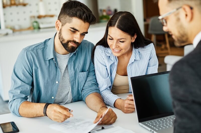 young couple discussing paperwork with mortgage adviser